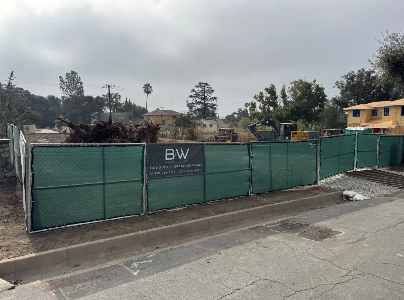 The same Altadena fence line seen from across the street, showing how the banner reads at normal passing distance